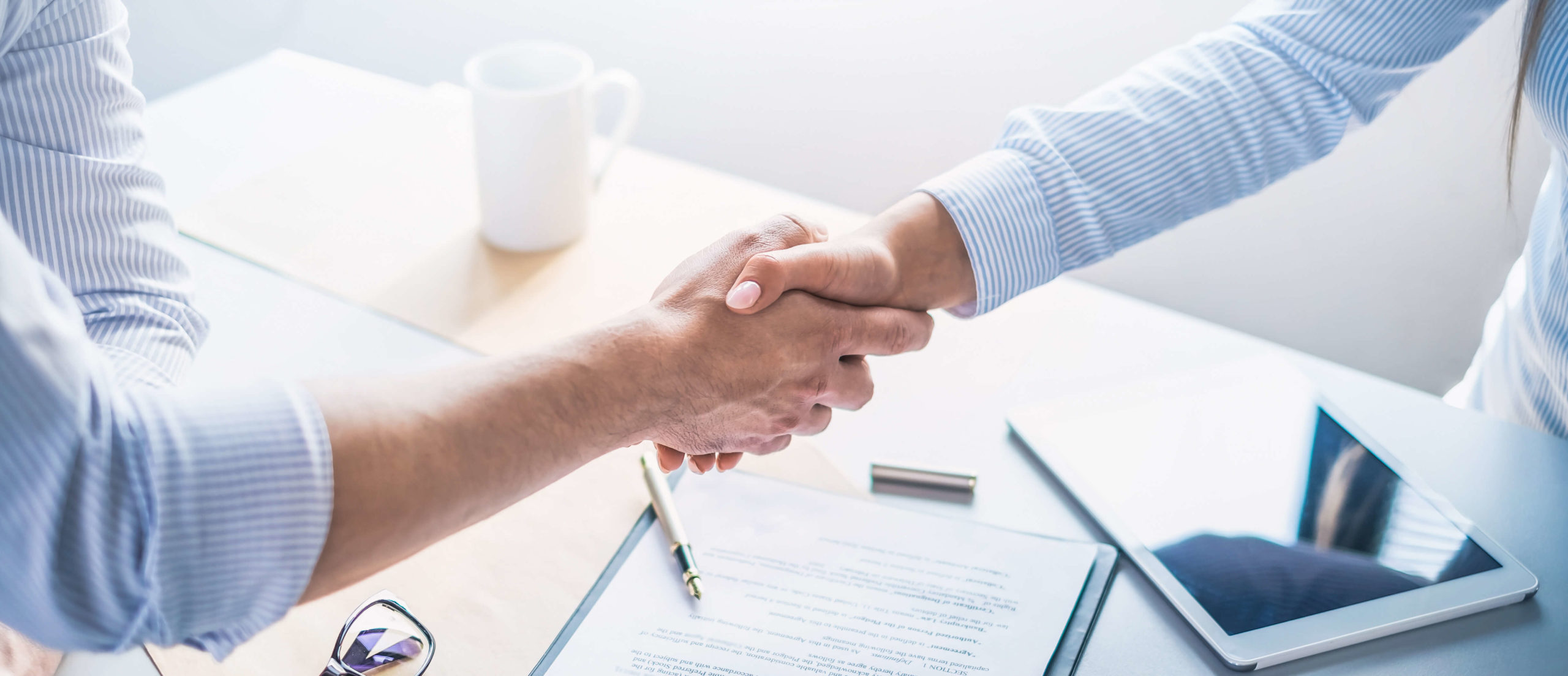 Business banking - close-up of two hands shaking over paperwork